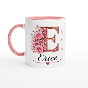 May include: White ceramic mug with a pink interior and handle. The mug features a floral design with the letter "E" in pink glitter, pearls, and roses. The name "Erice" is written below the letter.