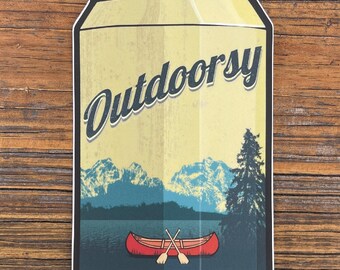 May include: A die-cut sticker shaped like a beverage can with a light yellow background. The word Outdoorsy is printed in dark blue script. Below, a landscape features a red canoe with two crossed oars on a lake, mountains, and a pine tree.