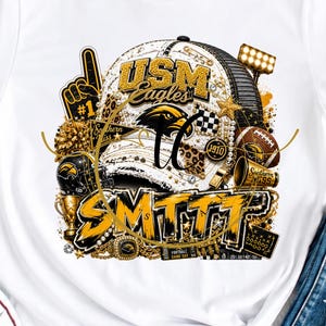 Könnte beinhalten: Ein weißes kurzärmeliges T-Shirt mit einem Grafikdruck einer Baseballkappe mit dem Text USM Eagles und SMTTT, umgeben von sportlichen Motiven wie einem Football, einem Schaumstofffinger und Stadionflutlicht in Gold- und Schwarztönen.