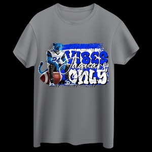 May include: A gray t-shirt featuring a blue jaguar with a football and the words "Vibes Jaguars Only" in a graffiti-style design. The jaguar is wearing a jersey with the number 24.