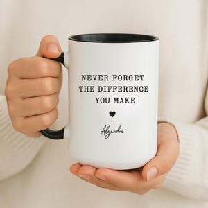 Puede incluir: Taza de cerámica blanca con interior y asa negros. La taza presenta el texto "NEVER FORGET THE DIFFERENCE YOU MAKE", un símbolo de corazón y el nombre "Alejandra" en cursiva.