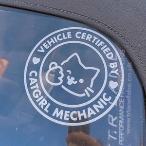 May include: A white sticker with a black circle and the text "Vehicle Certified by Catgirl Mechanic" with a cartoon cat inside the circle.