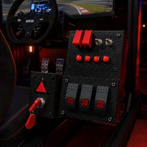 May include: A black carbon fiber textured button box for racing simulators featuring two red flip switches with safety covers, two metal toggle switches, four round red push buttons, three rectangular red illuminated rocker switches, and a red ignition key.