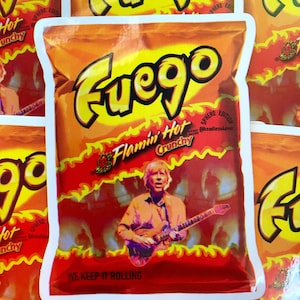 May include: A red and yellow bag of chips with the words "Fuego Flamin' Hot Crunchy" and "We Keep It Rolling" printed on it. The bag features a cartoon image of a person playing a guitar.