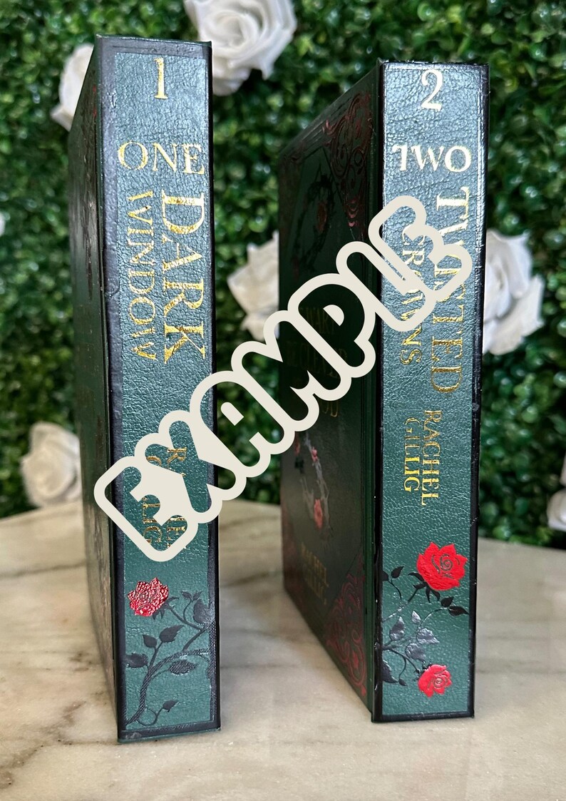 May include: Two hardcover books with green covers and gold lettering. The first book is titled "One Dark Window" and the second book is titled "Two Twisted Crowns" by Rachel Gillig.
