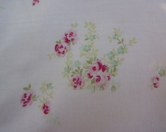May include: White fabric with a delicate floral pattern featuring pink and red roses and green leaves.