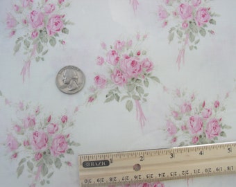 May include: White fabric with a repeating pattern of pink rose bouquets, green leaves, and pink ribbons. A US quarter coin and a ruler are included for scale. The fabric is likely used for sewing or crafting projects.