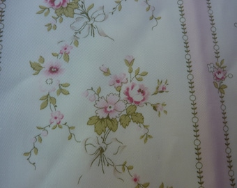May include: Floral fabric with a repeating pattern of pink roses, green leaves, and bows on a white background. Vertical stripes with a leaf and circle design border the floral pattern. The fabric has a soft, delicate appearance.