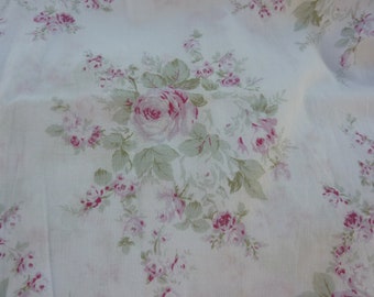 May include: White fabric with a pink and green floral pattern. The fabric features a repeating design of roses and leaves.