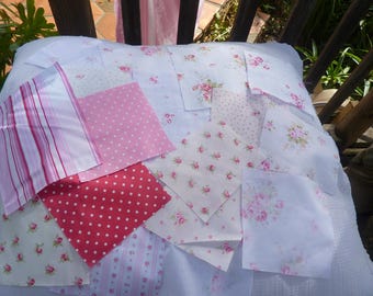May include: A collection of fabric squares in various patterns and colors, including pink polka dots, red polka dots, and floral prints. The fabrics are arranged on a white surface, suggesting a quilting or crafting project.