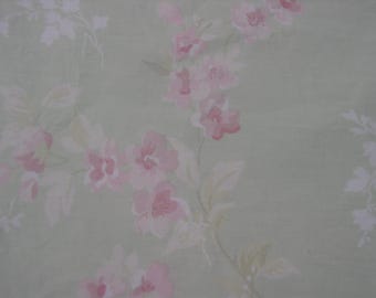 May include: A pale green fabric with a delicate floral pattern. The flowers are pink and white and have a watercolor effect.