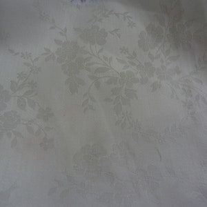 May include: White fabric with a subtle embossed floral pattern. The pattern features delicate flowers and leaves.