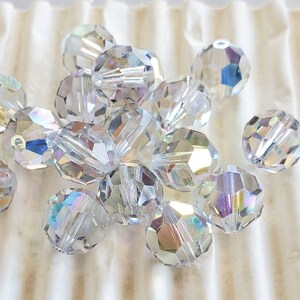 Può includere: Un gruppo di perline di cristallo trasparenti e sfaccettate. Le perline hanno una lucentezza iridescente, che riflette un arcobaleno di colori. Le perline sono rotonde con molteplici sfaccettature, creando un effetto scintillante. Queste perline sono adatte per la creazione di gioielli e l'artigianato.