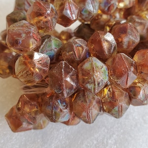 May include: A pile of iridescent brown glass beads with a faceted, star-shaped design.