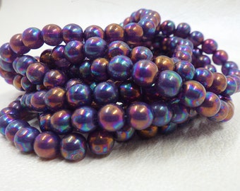 May include: A strand of iridescent purple and brown glass beads. The beads are round and have a smooth, shiny finish.