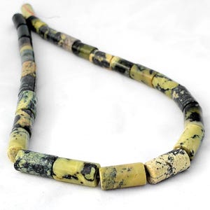 May include: Strand of cylindrical beads in shades of green, yellow, and black. The beads have a natural, speckled appearance, strung together on a thin, red string. The beads are approximately 0.5 inches in length.