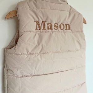 May include: A beige puffer vest with a brown embroidered name "Mason" on the back.