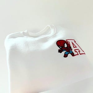 May include: White sweatshirt with an embroidered Spiderman character and the letter "A" in red.