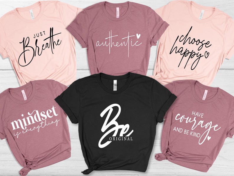 May include: A collection of six t-shirts in various colors, including pink and black. Each shirt features a different inspirational phrase in a stylish font, such as "Just Breathe" and "Be Original."