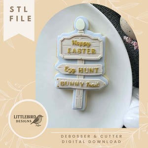 May include: A light blue and beige Easter-themed signpost cookie with the words "Happy Easter", "Egg Hunt", and "Bunny Trail". The image also includes the text "STL FILE", "Littlebird Designs", and "Debosser & Cutter Digital Download".