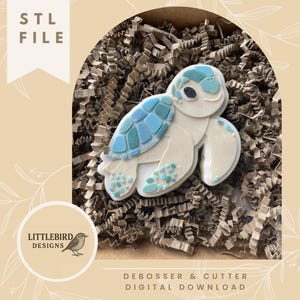 May include: A white and blue turtle-shaped cookie cutter and debosser digital download. The turtle has a light blue shell with darker blue accents. The image includes the text "STL FILE" and "DEBOSSER & CUTTER DIGITAL DOWNLOAD".