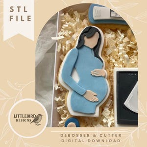 Könnte beinhalten: Ein Keksausstecher-Set mit einer schwangeren Person in einem blauen Kleid, einem Schwangerschaftstest und einem Ultraschallbild. Das Set ist in einer Box mit Papierfüllung verpackt. Der Text "STL FILE" und "DEBOSSER & CUTTER DIGITAL DOWNLOAD" sind sichtbar.