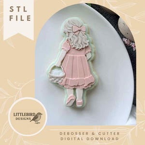 Könnte beinhalten: Ein rosa Ausstecher in Form eines Mädchens mit einem Korb voller Eier, auf einem weißen Teller. Der Ausstecher hat eine hellgrüne Kontur. Text: "STL FILE" und "DEBOSSER & CUTTER DIGITAL DOWNLOAD". Design von Littlebird Designs.