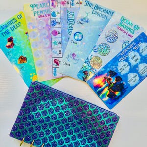 May include: A collection of mermaid-themed scratch-off cards and a matching glittery mermaid scale-patterned wallet. The cards feature titles like "Treasures of the Deep" and "Mermaid's Treasure Hunt". The wallet is blue and purple.
