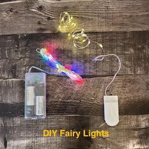 May include: DIY fairy lights with a battery pack and multi-colored LED lights. The lights are strung on a thin wire and are shown in a bundle and spread out. The battery pack is clear and contains two AA batteries.