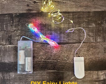 May include: DIY fairy lights with a battery pack and multi-colored LED lights. The lights are strung on a thin wire and are shown in a bundle and spread out. The battery pack is clear and contains two AA batteries.