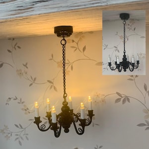 May include: A black metal chandelier with eight candle-style lights. The chandelier is hanging from a chain and has a decorative design.