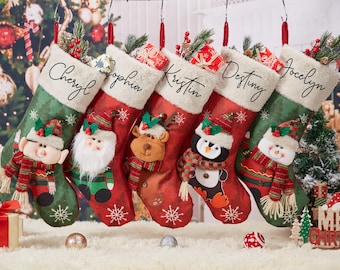May include: Christmas stockings in red and green with personalized names: Cheryl, Sophia, Kristin, Destiny, and Jocelyn. Each stocking features a different festive character, including an elf, Santa, a reindeer, a penguin, and a snowman.