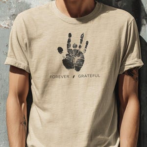 May include: A beige t-shirt with a black handprint graphic and the text "FOREVER GRATEFUL".