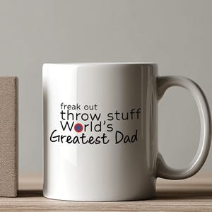 May include: White ceramic coffee mug with black text that reads "freak out throw stuff World's Greatest Dad".