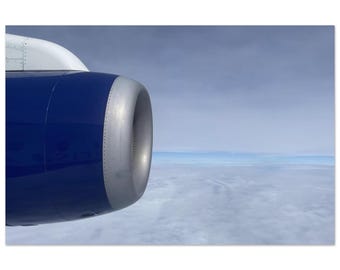 Può includere: Primo piano di un motore di aereo, con un esterno blu intenso e un'entrata d'aria argentata. L'immagine mostra il motore sullo sfondo di un cielo nuvoloso. La foto mette in risalto il design del motore e l'immensità del cielo.