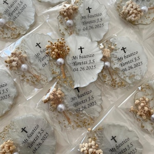 Peut inclure: Etiquettes rondes en résine blanche avec des paillettes dorées et des fleurs séchées. Chaque étiquette présente une croix et le texte "Mi bautizo Yaretzi J.S 04.26.2025".