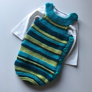 May include: A striped knitted baby sleeping bag in teal and green with turquoise buttons.
