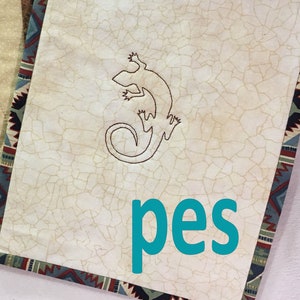May include: Two beige tea mats with embroidered lizard designs. The mats have brown and green borders. The text "SEW Artistic DESIGNS" and "pes" are visible on the right mat.