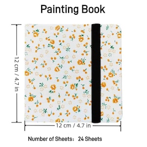 May include: A white painting book with a floral pattern and a black elastic closure. The book measures 4.7 inches by 4.7 inches and contains 24 sheets.