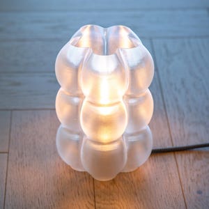 Yoli: Luminária de mesa, cabeceira e escrivaninha moderna. Luz ambiente, original e suave. Disponível em rosa, vermelho, azul, verde, roxo e amarelo, com formato ondulado. Fabricada no Reino Unido. Transparente