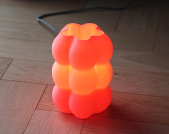 Yoli: Luminária de mesa moderna para cabeceira. Luz ambiente, inusitada e suave. Disponível em rosa, vermelho, azul, verde, roxo e amarelo. Formato ondulado. Fabricada no Reino Unido.