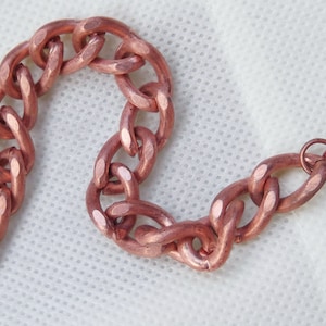 May include: A copper chain bracelet with a hammered finish. The bracelet has a lobster clasp closure.