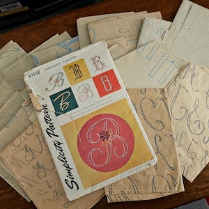 May include: A collection of vintage Simplicity Pattern embroidery transfer sheets featuring various alphabet letter designs. The primary envelope is labeled 4040B and displays multiple styles of the letter B in red, green, and yellow color blocks.