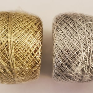 May include: Two spools of metallic thread, one gold and one silver. The thread is wrapped in a criss-cross pattern.
