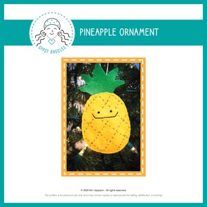 May include: A felt pineapple ornament with a smiling face, stitched with yellow thread. The ornament is hanging on a green Christmas tree with white lights.