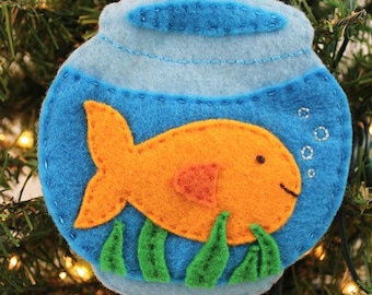 May include: Felt Christmas ornament shaped like a fishbowl with a gold fish inside. The fishbowl is blue with a white rim and the fish is orange with a red fin. There are green seaweed plants at the bottom of the bowl.