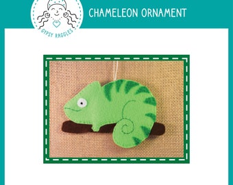 May include: A green felt chameleon ornament with a white eye, sitting on a brown felt branch. The ornament is hanging from a string. The text "GYPSY RAGGLES" and "CHAMELEON ORNAMENT" are visible in the image.