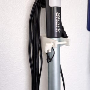 May include: A white ceramic mug with a black handle and the text "But First, Coffee" in a bold, black font. The mug is set against a blurred background, suggesting a cozy setting.