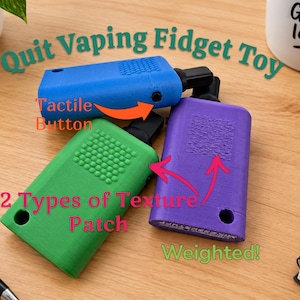 Puede incluir: Tres juguetes fidget rectangulares en azul, verde y morado, cada uno con una boquilla negra, un botón táctil y dos parches de textura distintos en la superficie. El texto Quit Vaping Fidget Toy, Tactile Button, 2 Types of Texture Patch y Weighted es visible.