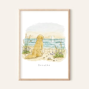 May include: A framed watercolour print featuring a golden dog sitting on a sandy beach, looking out at the blue ocean waves. Tall beach grass and small purple flowers grow in the sand. The word Breathe is printed in black text below the illustration.
